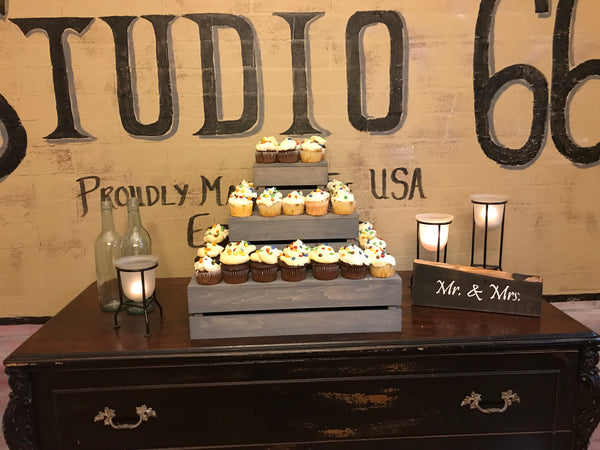 Farmhouse-style cupcake stand in antique gray holding cupcakes at a rustic wedding dessert table.