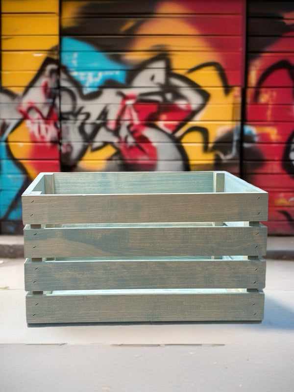 Vintage blue stained wood crate placed in front of colorful graffiti wall, rustic and urban.