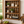 Early American wooden wall shelf with farmhouse decor, plants, candles, and books mounted on a kitchen wall