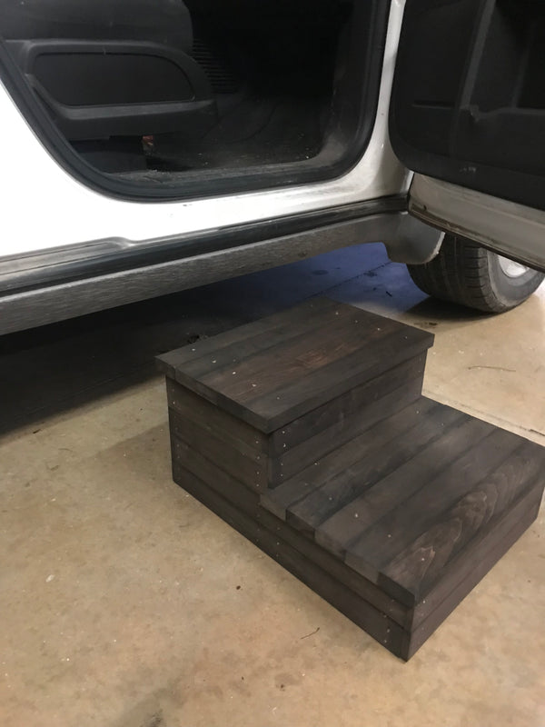Wooden 2-step stool in dark walnut finish placed beside a car door for easy entry.