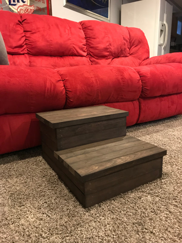 Wooden pet and child 2-step stool in dark walnut finish next to a red sofa.