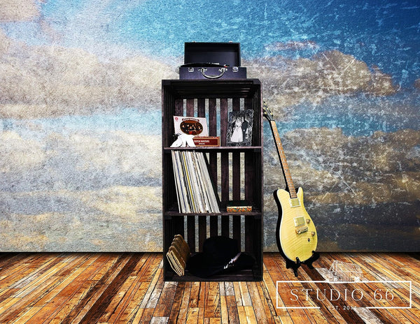 Dark stained 3-tier wooden vinyl record stand with records, turntable, and guitar.