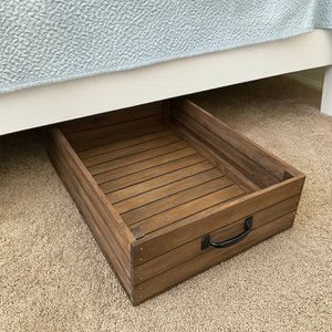 Rustic wooden under-bed storage drawer shown under white bed frame
