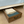 Rustic wooden under-bed storage drawer with folded cream and green blankets neatly stored inside.