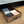 Rustic wooden under-bed storage drawer filled with folded jeans, shirts, and casual clothes for organized bedroom storage.