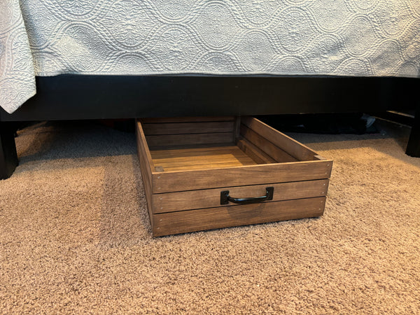 Wooden under-bed storage drawer partially pulled out from under bed