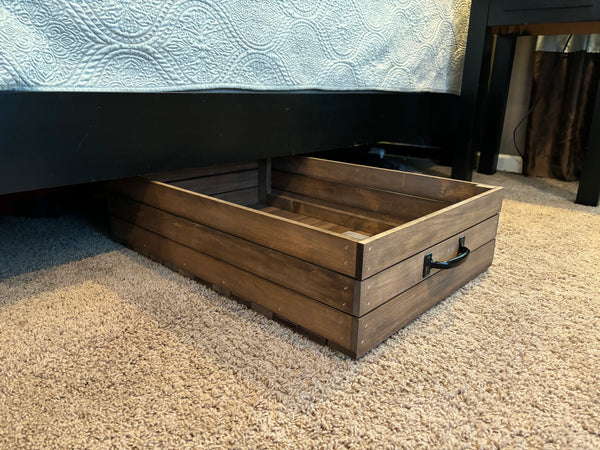 Side view of rolling wooden under-bed storage drawer with black handle