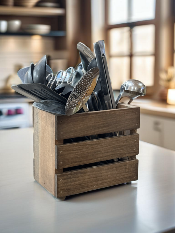 Rustic wooden utensil holder crate filled with cooking utensils on counter