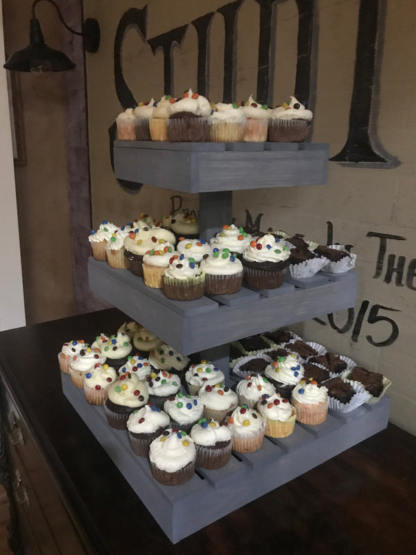 Rustic gray 3-tier cupcake stand with cupcakes styled for a wedding reception.
