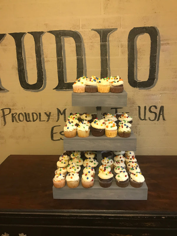 Rustic 3-tier antique gray cupcake stand with cupcakes at a wedding dessert table.