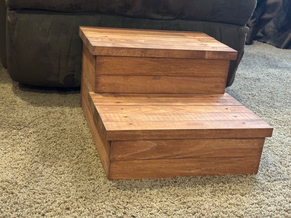 Cherry stained two-step wooden pet stairs beside couch on carpet