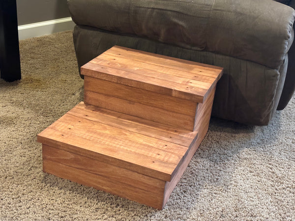 Rustic cherry wood pet steps two tiers high next to furniture