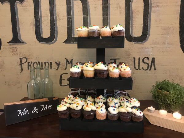 Farmhouse-style dark wood cupcake stand with cupcakes on display for a rustic party celebration.