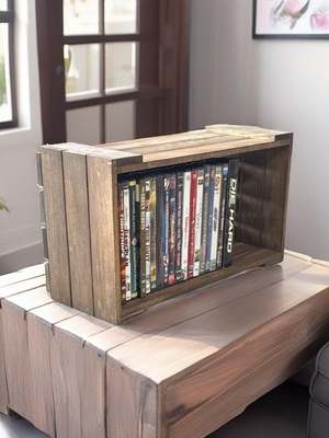 Rustic wooden DVD holder crate on table, filled with movies.