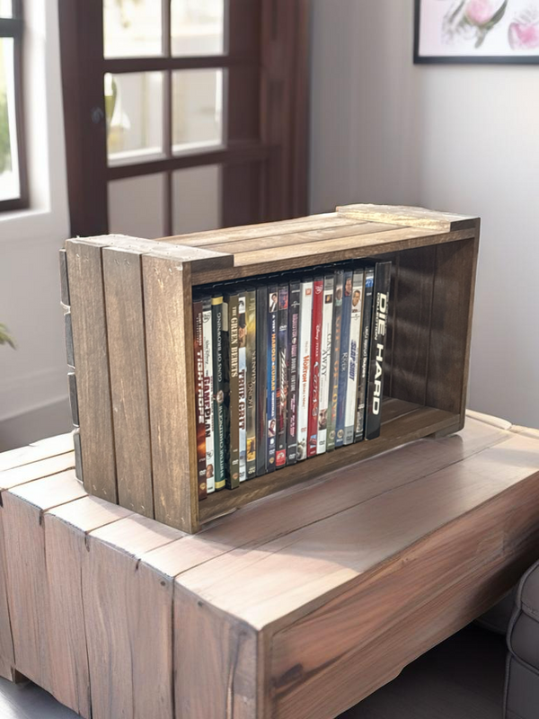 Rustic wooden DVD holder crate on table, filled with movies.