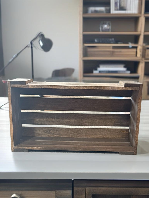 Wooden DVD holder crate on tabletop with bookshelf in background.