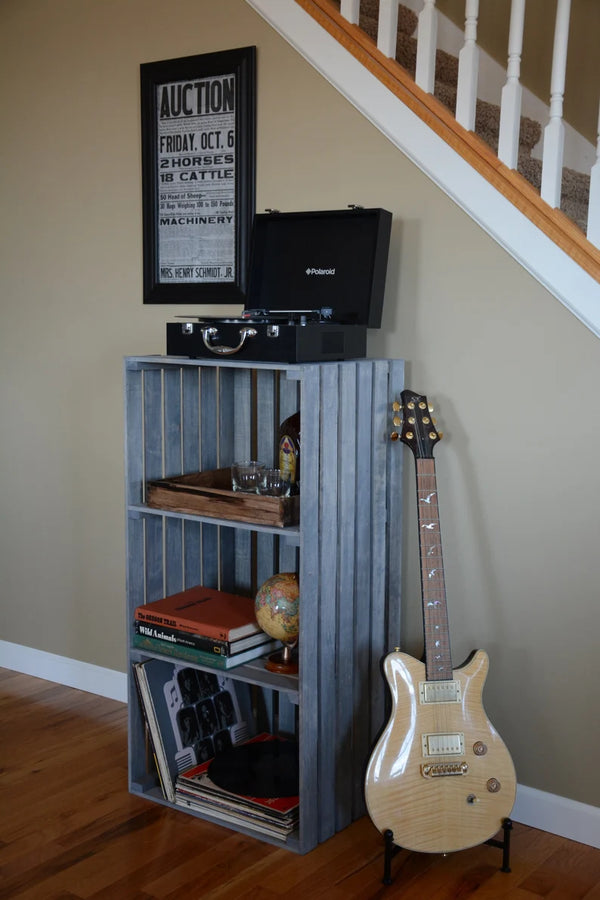 Rustic gray 3-tier vinyl record storage stand styled with books, globe, and guitar.