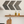 Rustic gray chevron wall art set of 3 mounted above kitchen shelf with cutting boards and oil bottles.