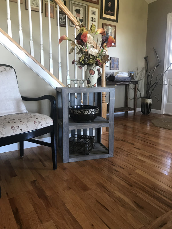 Rustic gray wooden end table styled with floral arrangement.