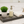 Rustic gray wooden tray styled with soap dispenser, plant, and towel in bathroom.