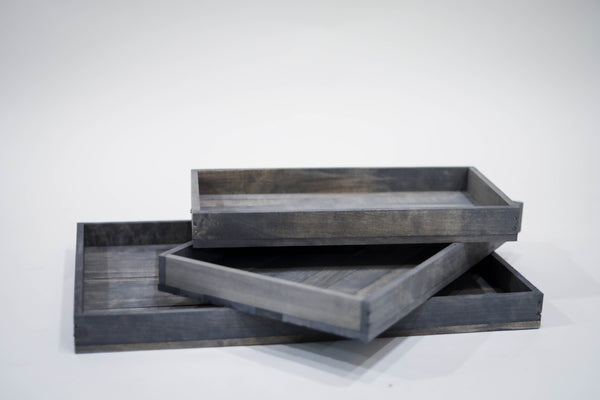Set of rustic gray trays stacked in various sizes on white background