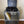 Gray 2-tier wooden turntable stand holding vinyl records and record player.