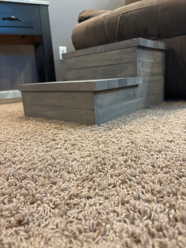Rustic gray wooden 2-step pet stairs placed in a living room, designed to help small dogs and cats reach furniture.