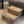 Angled view of a rustic medium brown 2-step stool on carpet in front of a recliner.