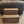 Front view of medium brown stained 2-step wooden stool placed in front of a recliner.