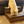 Small fluffy dog using a medium brown stained wooden 2-step stool in front of a couch.