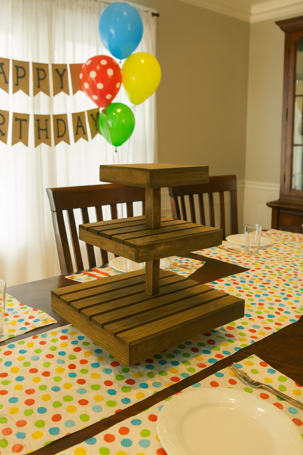 Wooden medium cupcake stand filled with cupcakes at a birthday party table setup.