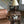 Medium farmhouse wooden end table with lamp, ceramic birds, and magazines for rustic decor.