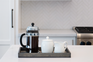 Rustic gray wood serving tray with French press and creamers in kitchen