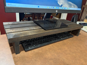 Close-up angled view of 24-inch dark wood monitor riser with slatted top.