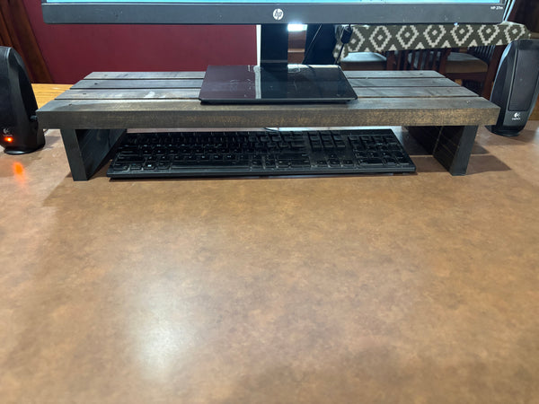 Dark stained 24-inch wooden monitor riser with keyboard neatly stored underneath.