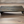 Handmade rustic wooden monitor stand in dark stain shown on wood floor.