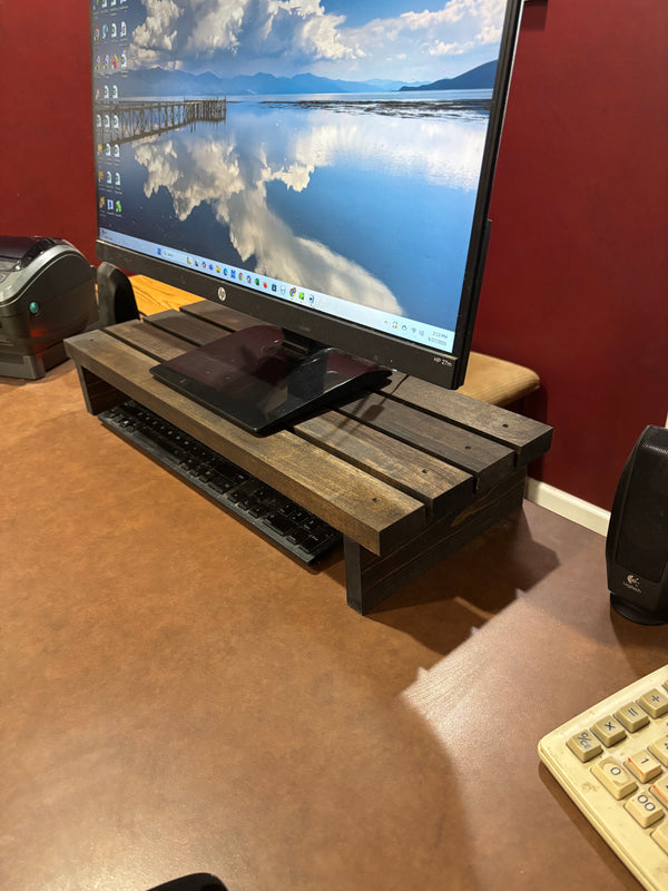 Side view of dark wood monitor stand with HP screen and keyboard storage space.