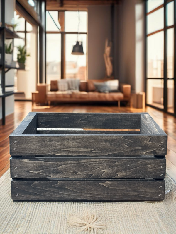 Small dark wood crate in modern living room on woven rug, rustic storage solution.