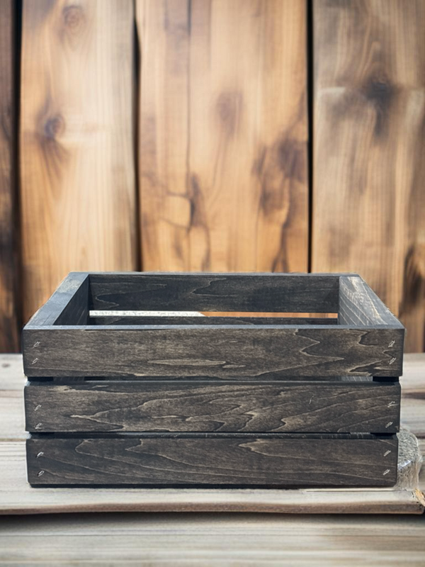 Small dark farmhouse crate against wood wall background, rustic storage box.