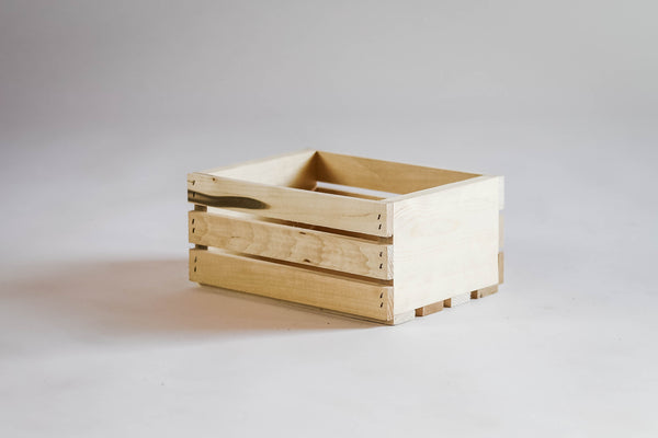 Side view of small natural wooden storage crate on white background