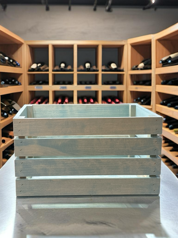 Vintage blue stained wooden crate displayed in wine cellar with wood shelves.
