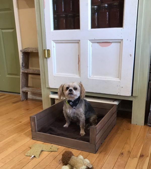 Handmade wooden dog bed with medium brown stain and cozy blanket