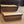 Front angle view of handmade 2-tier wooden pet steps in Early American finish beside a brown sofa.