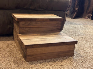 Front angle view of handmade 2-tier wooden pet steps in Early American finish beside a brown sofa.