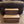 Straight-on view of 2-tier wooden pet stairs in Early American stain against a recliner.