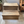 Wooden 2-step pet stairs in Early American finish styled in a bright farmhouse living room with a wicker basket plant.
