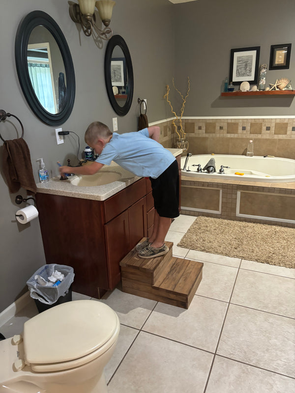 Child using Early American 2-tier wooden steps at bathroom sink for added height.