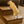 Small tan dog climbing 2-step wooden pet stairs in Early American finish beside sofa.
