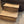Angled view of rustic 2-tier wooden pet steps in Early American stain against carpet and brown recliner.